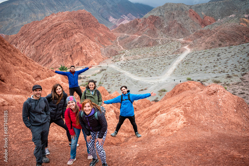 Grupo de turistas en la cumbre de un cerro colorado en Purmamarca, Argentina photo