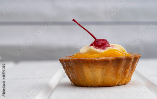 Tart with peaches and cherries cream close-up. Cake, sweet tartlet, dessert, on a light background, space for text, copy space, soft focus.