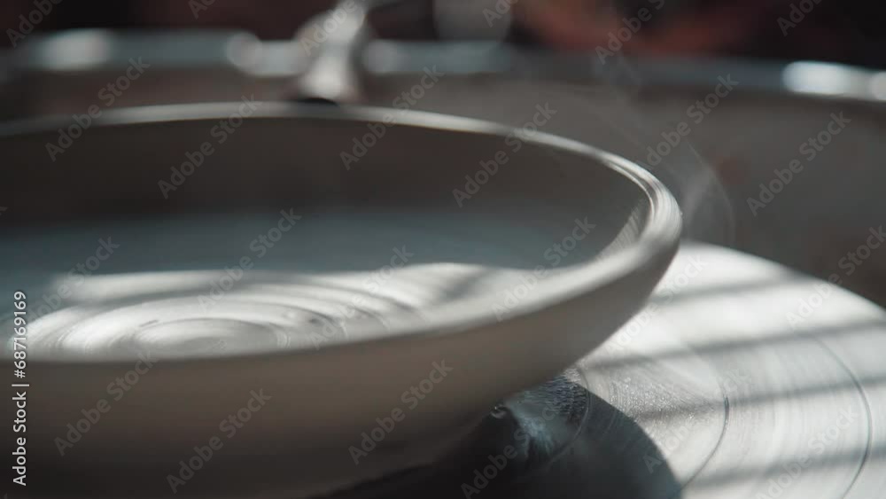 Clay product on a potter's wheel. Shot from the side, close-up. A plate made of clay rotates on a potter's wheel, smoke comes from clay - the potter dries the product No people. Clay product on a potter's wheel. Shot from the side, close-up. A plate made of clay rotates on a potter's wheel, smoke comes from clay - the potter dries the product No people.