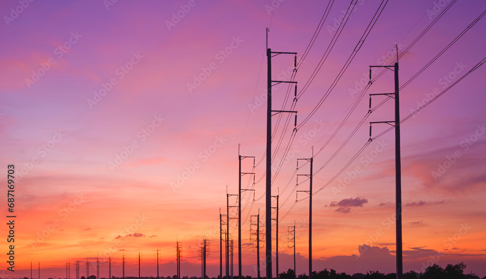 Silhouette row of electric poles with cable lines against colorful sunset sky background, low angle and widescreen view