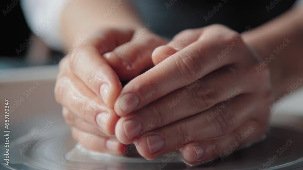 Wet hands of a female potter holding clay on a spinning wheel, close up. Creative process. Wet hands of a female potter holding clay on a spinning wheel, close up. Creative process.
