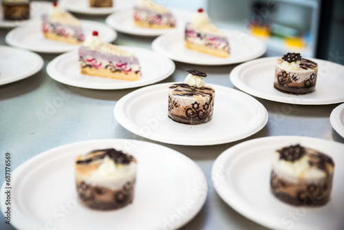 Detail of group of sweet colorful desserts and cakes on white plates. Pink punch cuts  curdled chocolate round cakes.