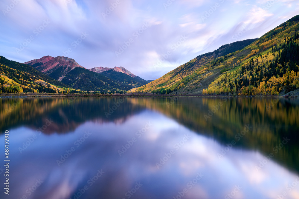 yellow aspen covered mountains and dreamy clouds reflected in a tranquil lake in Colorado
