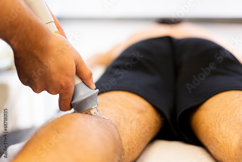 An unrecognizable adult man visits a physical therapy clinic for an ultrasound treatment to relieve calf pain. Ultrasound therapy on legs. Ultrasounds to heal muscle pain.