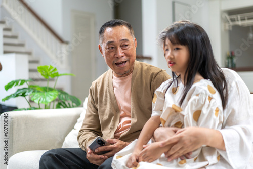 Portrait of happy love asian grandfather with grandmother and asian little cute girl enjoy relax at home.Young girl with their laughing grandparents smiling together.Family and togetherness