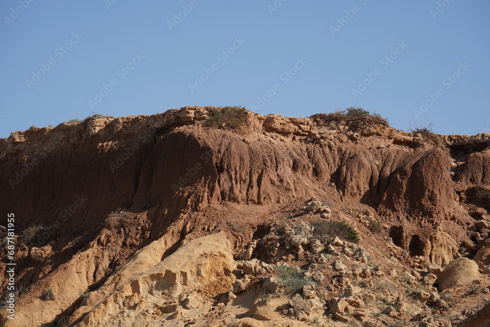 Rocky sea shore and blue sky on sunny  day. Seascape, Mediterranean coastline, layers of rock and stones