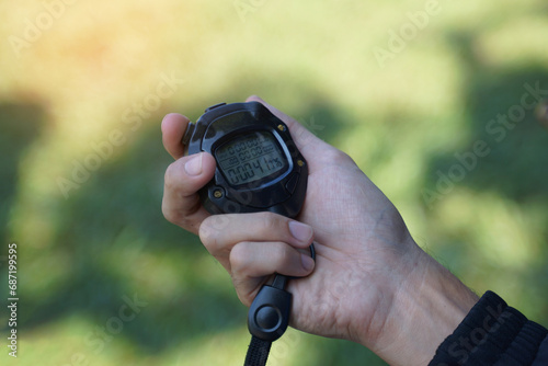 Coach holds a stopwatch to check the runners' speed statistics during practice. soft and selective focus.