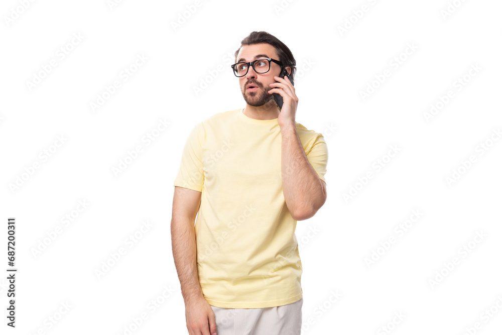 portrait of a casual caucasian guy with a beard in glasses dressed in a light t-shirt and talking on the phone portrait of a casual caucasian guy with a beard in glasses dressed in a light t-shirt and talking on the phone