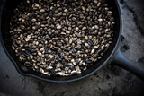 coffee beans being roasted in iron pot.