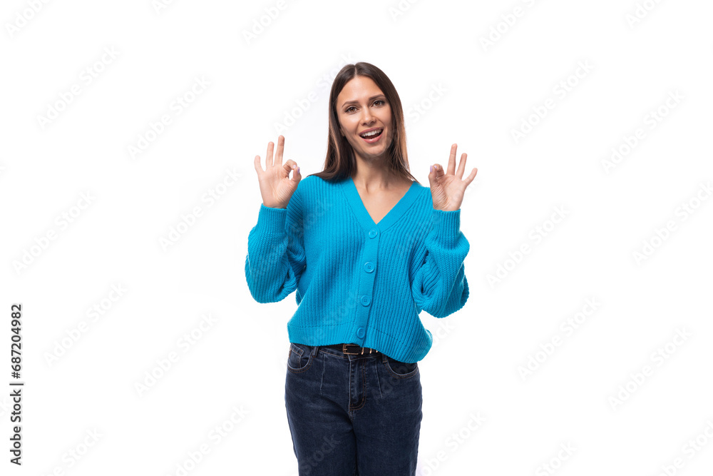 young charming brunette lady dressed in a blue V-neck sweater actively jests on a white background with copy space. advertising concept young charming brunette lady dressed in a blue V-neck sweater actively jests on a white background with copy space. advertising concept