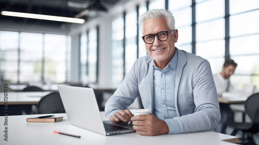 Middle aged man working on a laptop in his modern office Middle aged man working on a laptop in his modern office