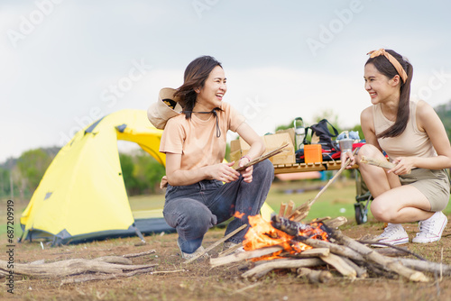 Happy Asian women light a fire near their camping site together prepare for cooking and warmth. Women enjoy camping activity.