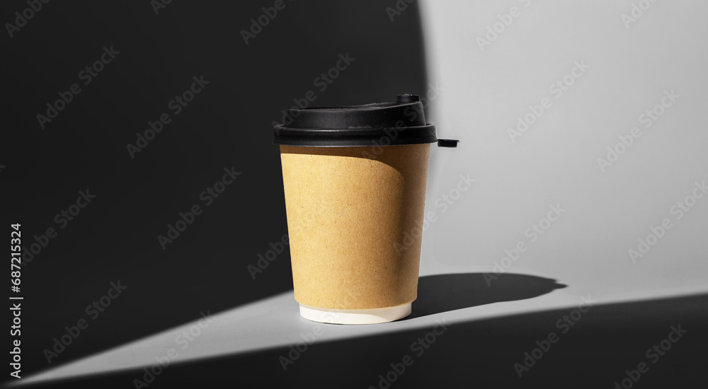 Craft brown paper cup mockup, coffee mug to go with black cap, lid in sunlight beam Craft brown paper cup mockup, coffee mug to go with black cap, lid in sunlight beam