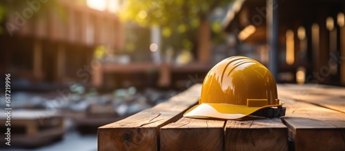 yellow safety helmet or hardhat, construction worker , is placed on wooden photo