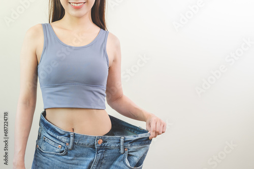 Shape slender, thin waist, attractive slim asian young woman, hand show shape her weight loss, wearing in big, large or oversize jeans, excess lose by diet and exercise. People body fit healthy.