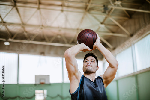 Young man shooting a basketball in an indoor basketball gym photo