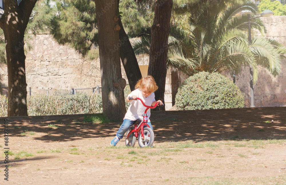 Little boy with blond hair, on his red bicycle, in a park, on a sunny day. Lifestyle-themed stock photography Little boy with blond hair, on his red bicycle, in a park, on a sunny day. Lifestyle-themed stock photography