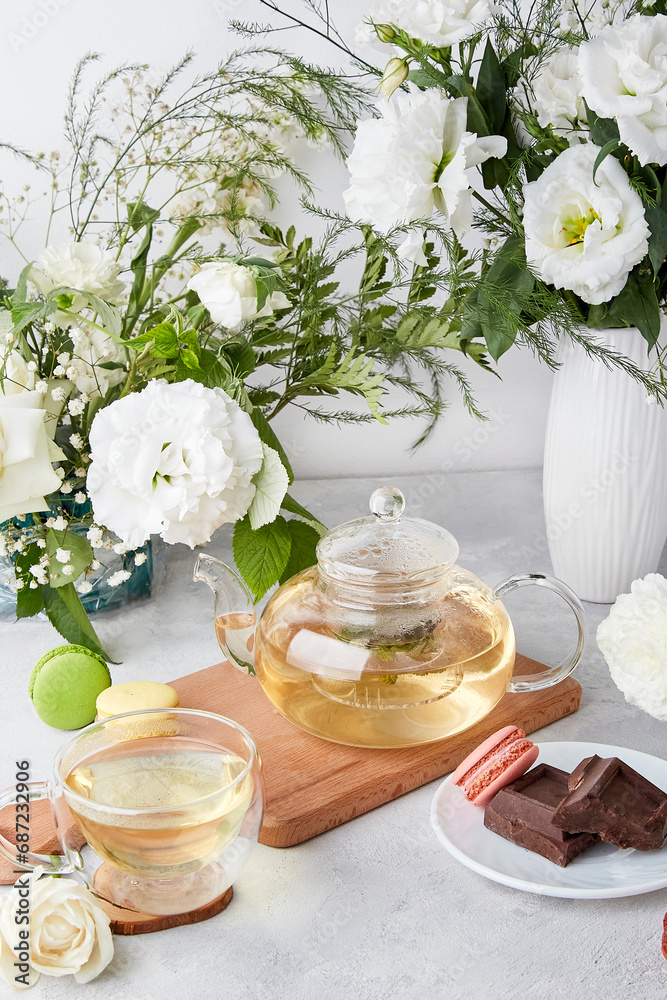Aesthetic table - teapot, cup, desserts, white flowers - time for yourself, cozy home concept.