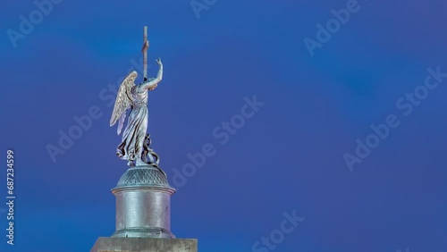 Night Timelapse of Angel Statue on Alexandria Column, Palace Square, Saint Petersburg, Russia. Close-Up View from Moyka River Quay, Illuminated Landmark photo