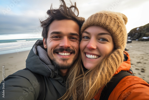 Portrait of happy young couple looking at camera at beach during winter