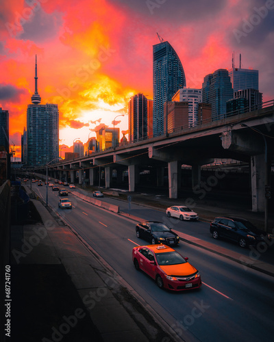 traffic driving through a sunset in Toronto with city skyline skyscrapers