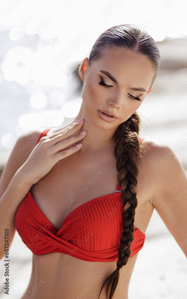beautiful woman with dark hair in elegant red swimming suit posing in the white stones beach in Cyprus beautiful woman with dark hair in elegant red swimming suit posing in the white stones beach in Cyprus