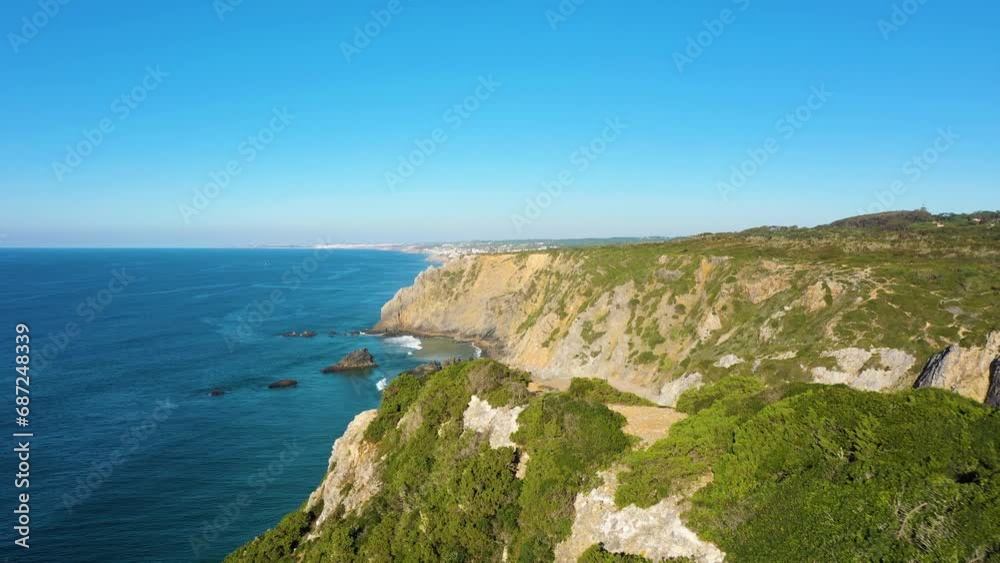Adraga Beach, Cliffs and Atlantic Ocean Waves. Portugal. Aerial View. Green Bushes. Drone Flies Forward over the Cliff, Tilt Down. Establishing Shot Adraga Beach, Cliffs and Atlantic Ocean Waves. Portugal. Aerial View. Green Bushes. Drone Flies Forward over the Cliff, Tilt Down. Establishing Shot