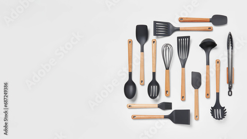 Mixed kitchen tools aligned on grey copy-space background.