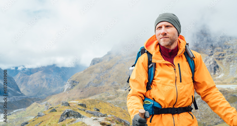 Portrait of caucasian man with backpack and trekking poles in Makalu Barun Park route near Khare. Mera peak climbing acclimatization active walk. Backpacker enjoying valley view. Active people concept