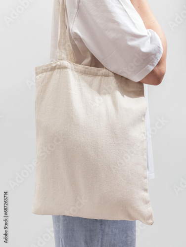 Modern woman carrying textile shopper, eco-friendly linen tote bag on shoulder