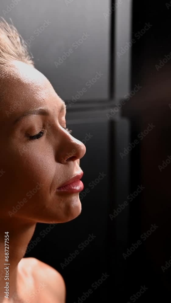 The artist sprays an instant tan on a woman's face. Vertical video.