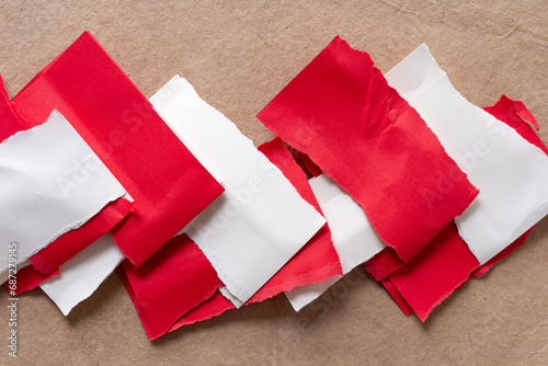torn and folded interlocking red and white paper stripes on plain brown paper