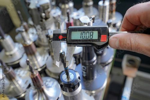 A worker measures the size with a caliper of tools for working on a CNC milling machine.