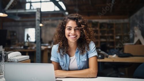 Cheerful woman sitting at a desk with a laptop in a warehouse surrounded by shelves stocked with boxes. photo