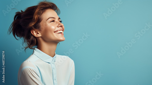 Portrait of young european fashionable female model, shot from the side, smiling, looking to the side, blue background photo