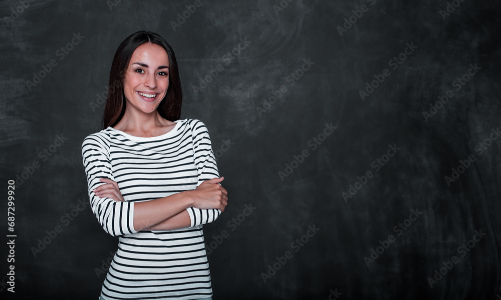 Close up photo of smiling cute happy young woman standing against blackboard in casual wear Close up photo of smiling cute happy young woman standing against blackboard in casual wear