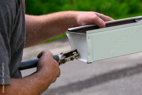 Hands of a Technician in the process of installing custom-made gutters on our home in Windsor in Upstate NY.  The skilled hands of a craftsman preparing gutters for installation.  
