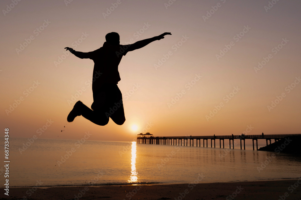 silhouette of a man walking on the beach at sunset