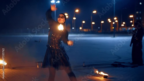 A dancing couple performing fire show outdoors at night. Artists move with burning props in hands. photo