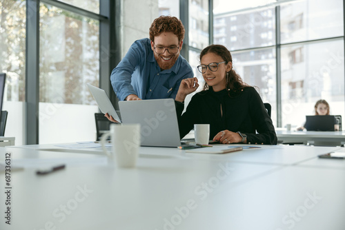 Two diverse business colleagues disscuss biz issue while use laptop in office background