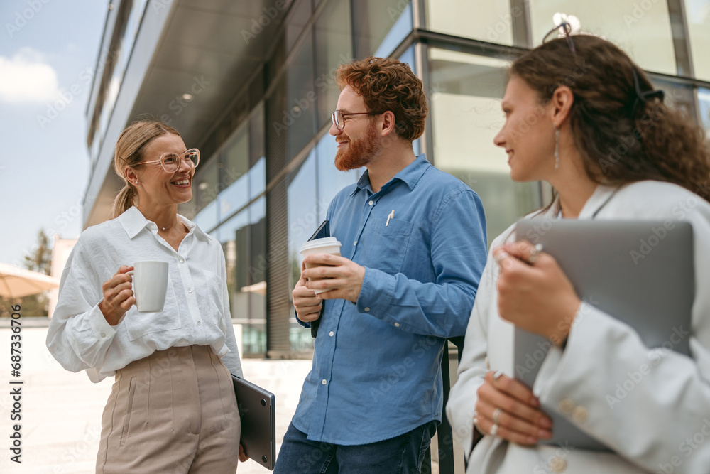 Smiling business colleagues talking and laughing during break time outside of office Smiling business colleagues talking and laughing during break time outside of office