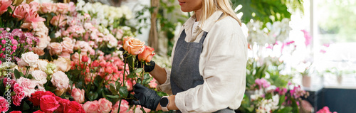 Woman florist flower shop owner hold roses on floral background. High quality photo #687337573