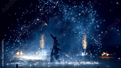 Beautiful dazzling fire show at night. Male performer dances with props producing bright sparkles. photo
