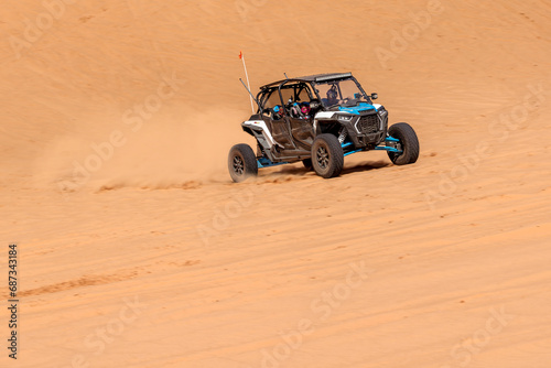 Obraz na plátně Polaris side by side kicking up dust in the sand dunes⠀