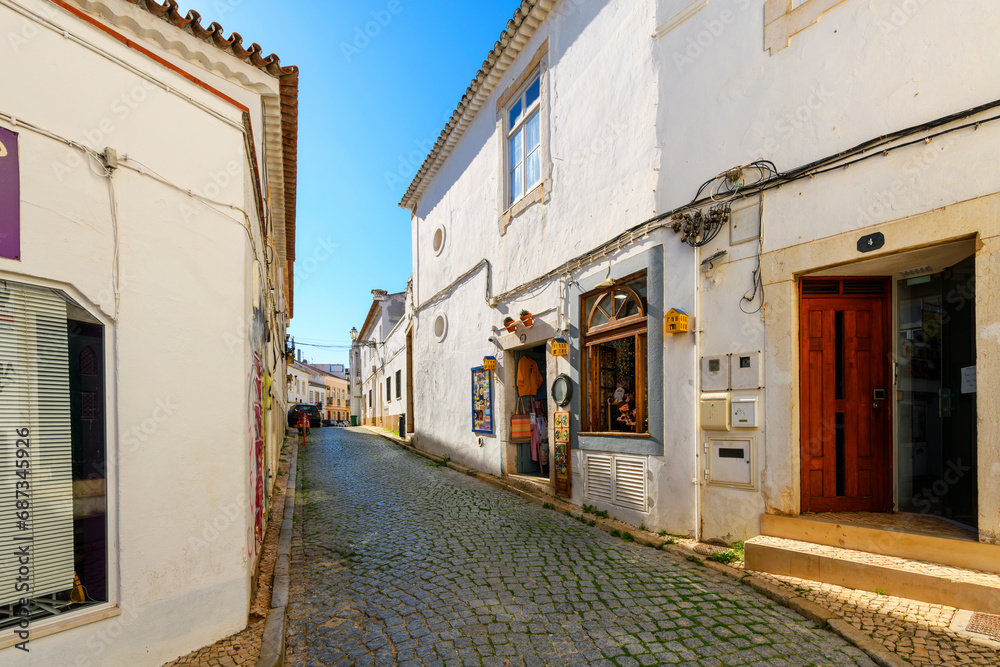 A picturesque tiled street of shops and sidewalk cafes in the historic old town center of seaside Lagos, Portugal, in the Algarve region of Southern Portugal. 