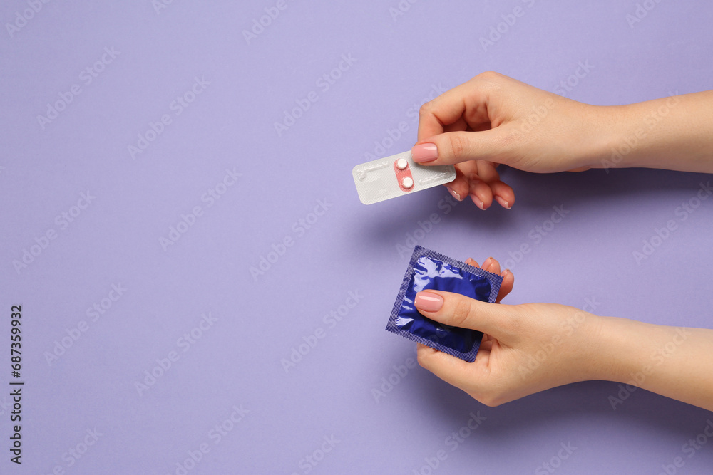 Woman holding condom and contraceptive pills on violet background, top view with space for text. Choosing birth control method - obrazy, fototapety, plakaty 