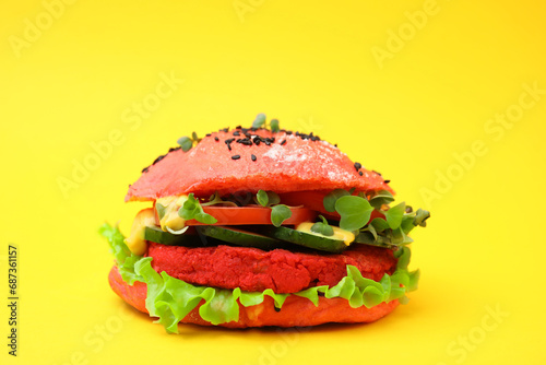 Tasty pink vegan burger with vegetables, patty and microgreens on yellow background, closeup