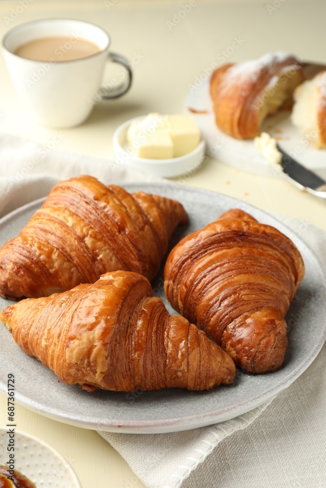 Plate with tasty croissants on beige table, closeup