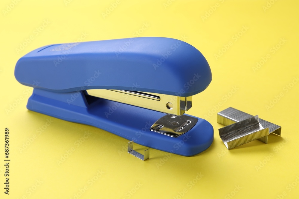 Blue stapler with staples on yellow background Blue stapler with staples on yellow background