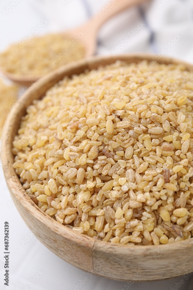Raw bulgur in bowl on table, closeup Raw bulgur in bowl on table, closeup